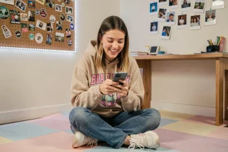 Jeune femme riant devant son smartphone dans une chambre décorée façon Gen Z, illustrant les codes et le langage TikTok
